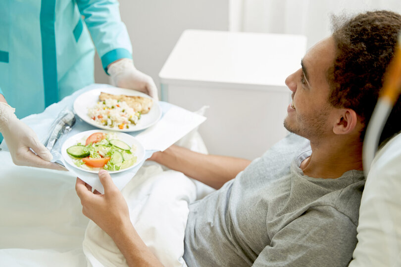Patient im Bett erhält Essen auf Tablett
