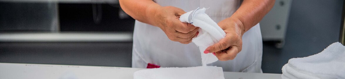Dussmann Lavador - Laundry Solutions Wäschereimitarbeiter/in faltet Wäsche