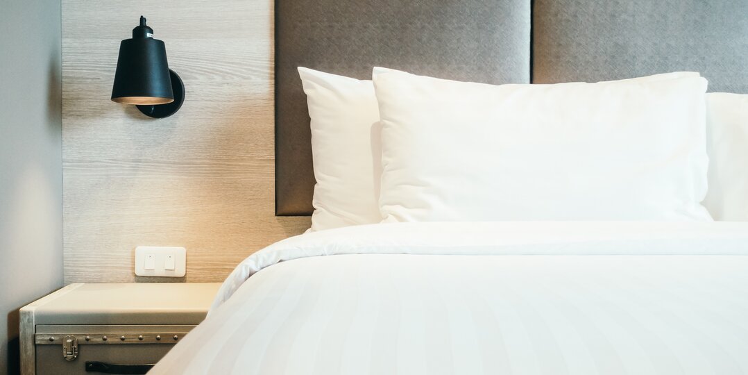 Dussmann Wäscheservice für das Hotelgewerbe und die Lebensmittelindustrie liefert saubere und hygienische Wäsche, die den Anforderungen dieser Branchen entspricht, und hält dabei strenge Hygiene- und Qualitätsprotokolle ein. | © <a href="https://www.freepik.com/free-photo/pillow-bed_1255051.htm#fromView=search&page=2&position=10&uuid=a7169df1-c8d3-4623-9cf3-a739261588af&query=pillow+on+hotel+bed">Image by mrsiraphol on Freepik</a>